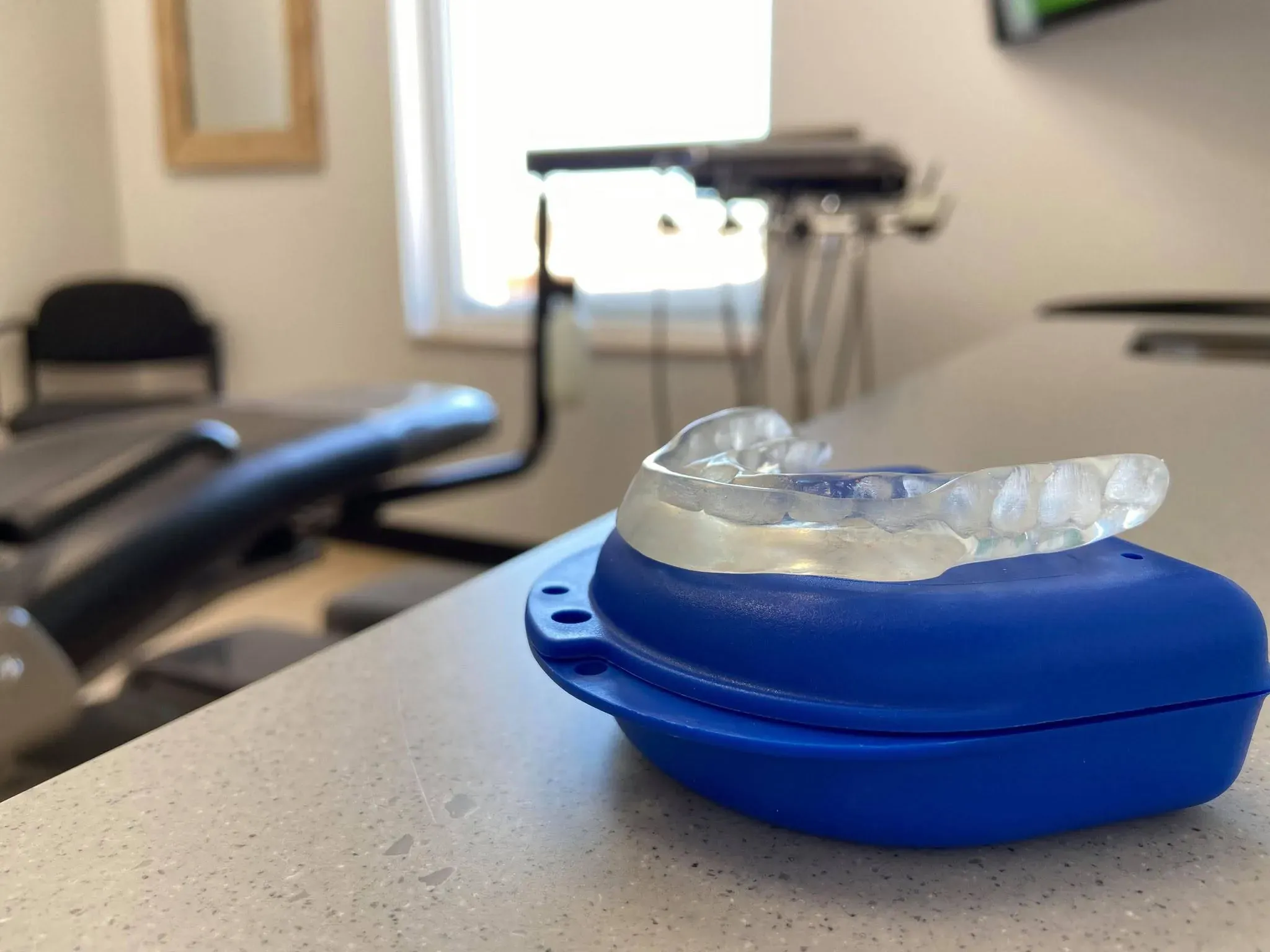 Une gouttière dentaire transparente dans son étui, sur le comptoir d'une salle de soin de la clinique.
